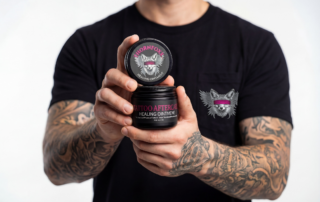 Man holding Thornfoxx Tattoo Aftercare Healing Ointment in tattoo studio – premium tattoo healing balm for all phases of tattoo recovery